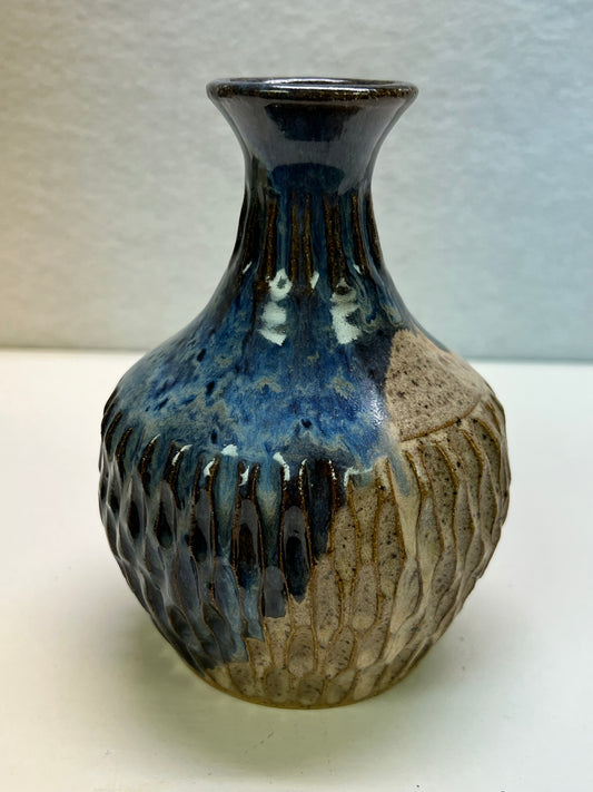 Handmade, wheel-thrown ball vase made by local potter in Colorado Springs. The vase has a narrow neck, flared rim, and balled, textured carved body in a speckled clay and cobalt glaze.